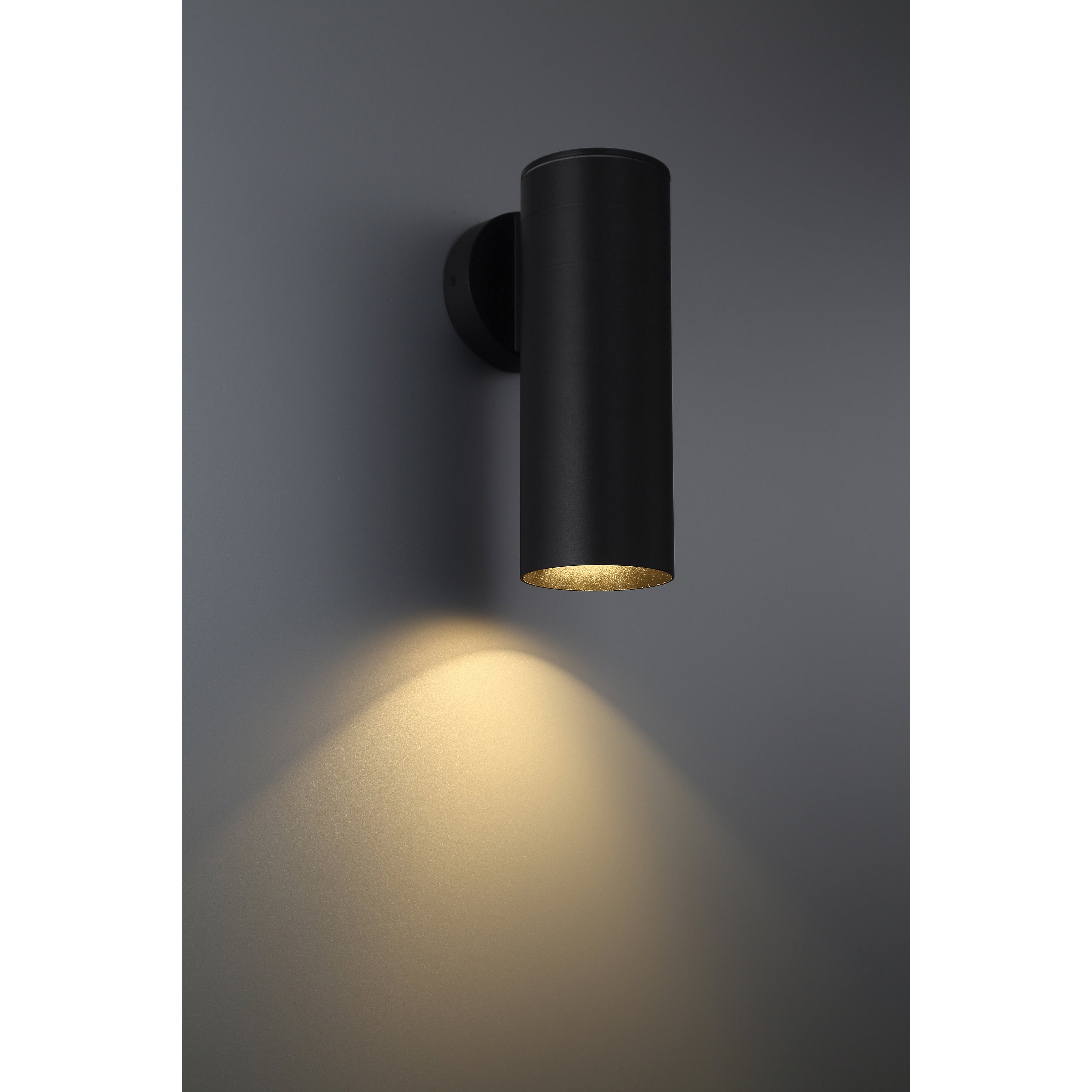 The Access Lighting Matira 1 Light Outdoor LED Wall Mount in black (20148LEDDMGLP) features a sleek cylindrical design that casts a warm, downward glow onto the gray wall.