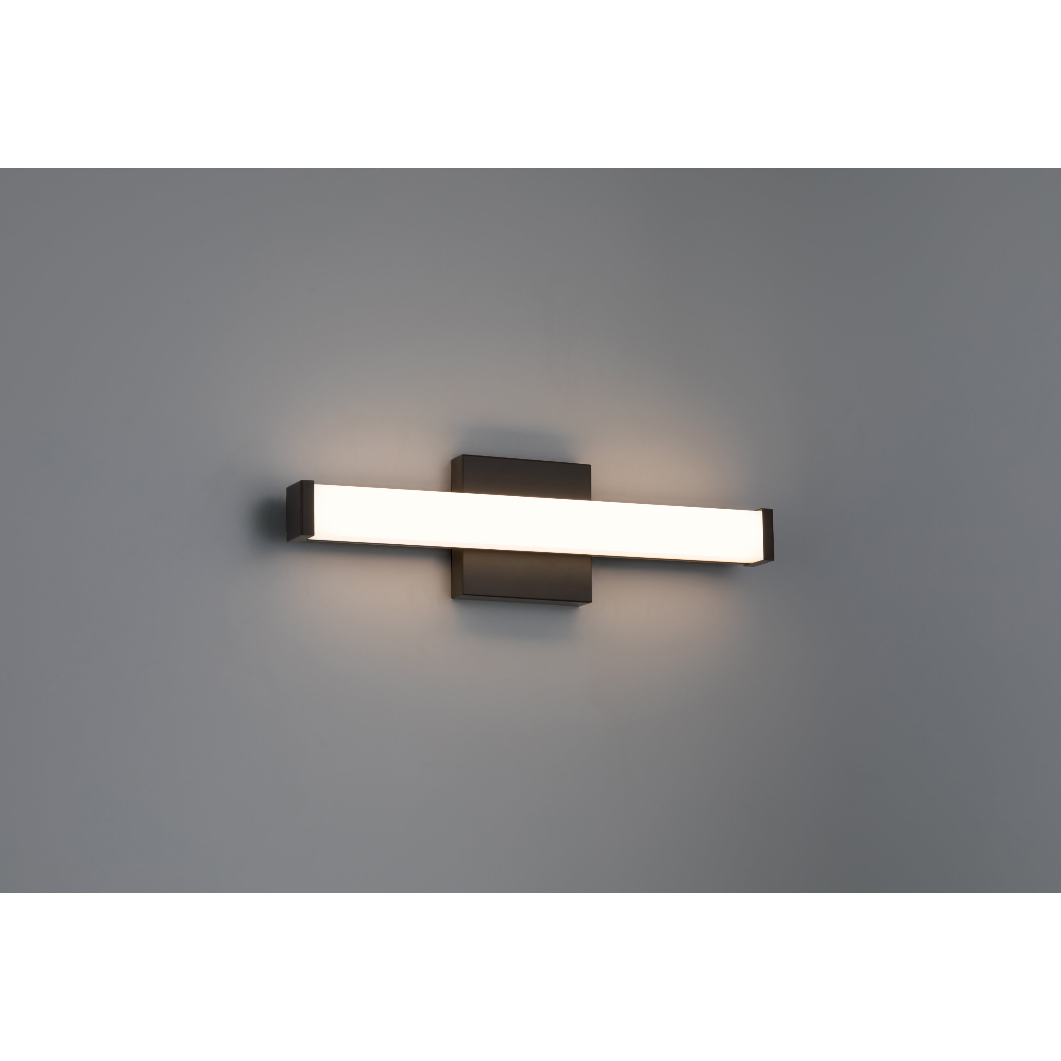 The Maxx 5CCT LED Vanity by Access Lighting is a modern, rectangular 18″ wall-mounted light fixture featuring a matte black base and a frosted horizontal shade, shown illuminated against a plain gray wall.