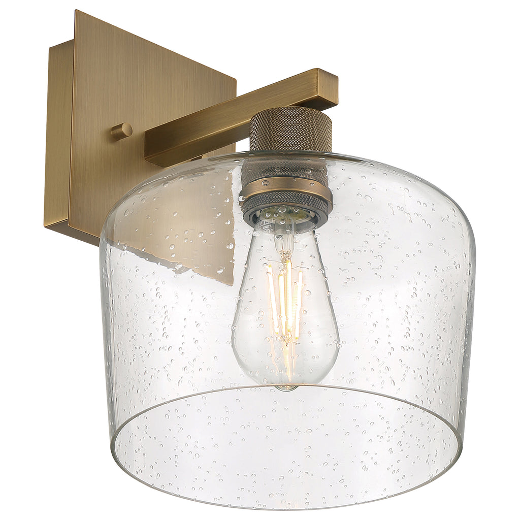 The Port Nine Chardonnay LED Wall Sconce by Access Lighting features an antique brushed brass base, a clear seeded glass shade, and a central exposed filament-style LED bulb.