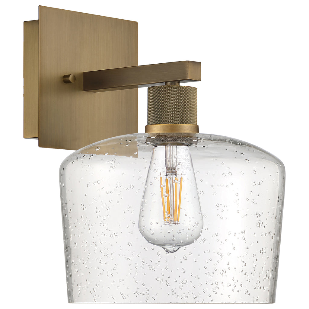The Port Nine Chardonnay LED Wall Sconce by Access Lighting features an antique brushed brass finish, a seeded glass shade, and a visible vintage-style bulb for a sophisticated wall-mounted accent.