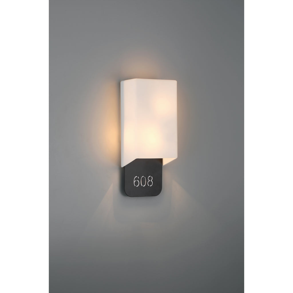 The Décor 2 Light Indoor LED Address Light with Braille by Access Lighting, featuring a frosted rectangular shade, is mounted on a gray wall above a black plaque displaying the number 608.